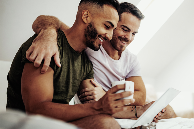 two men sitting, smiling, reading