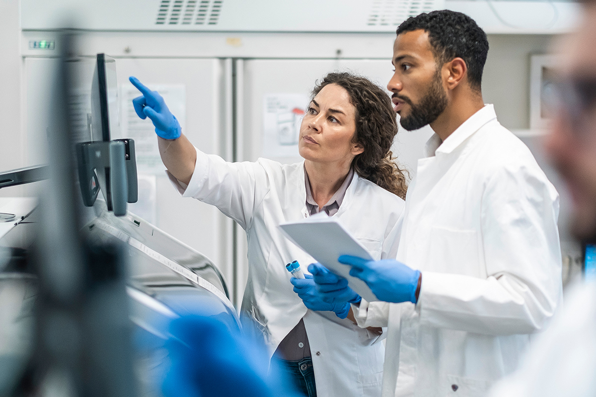 Lab employees point at a computer screen.
