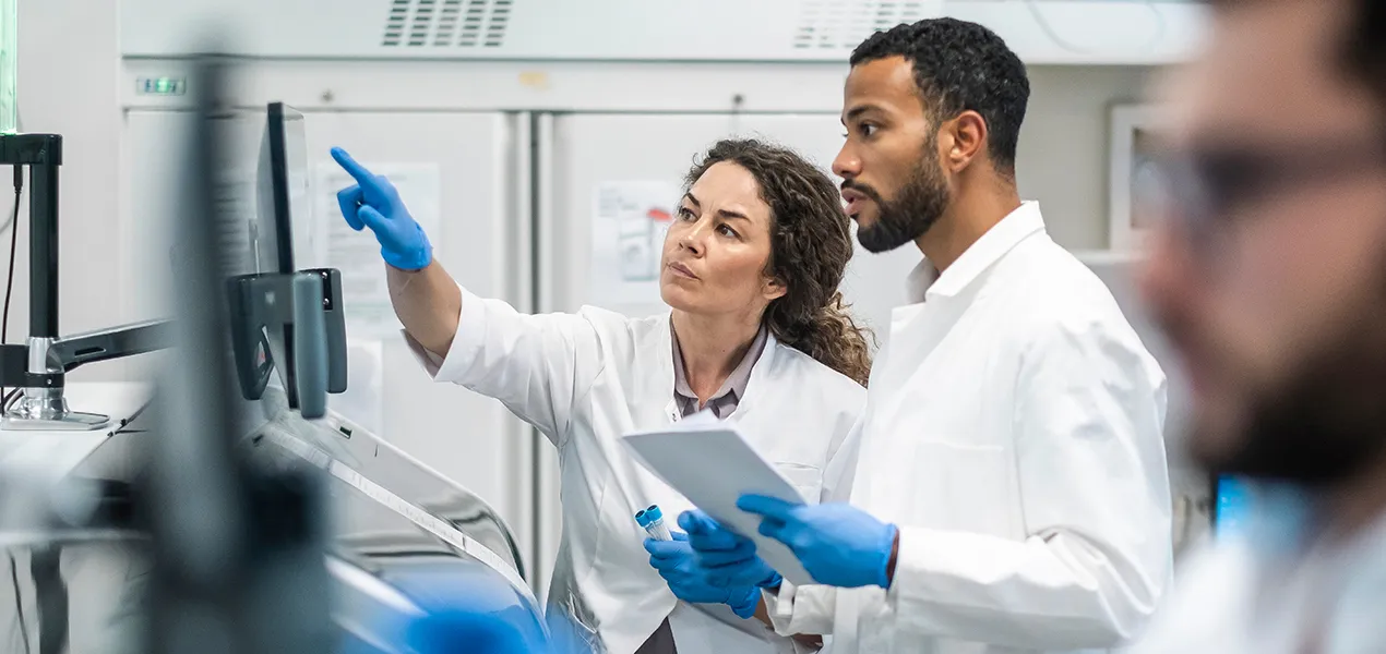 Lab employees point at a computer screen.